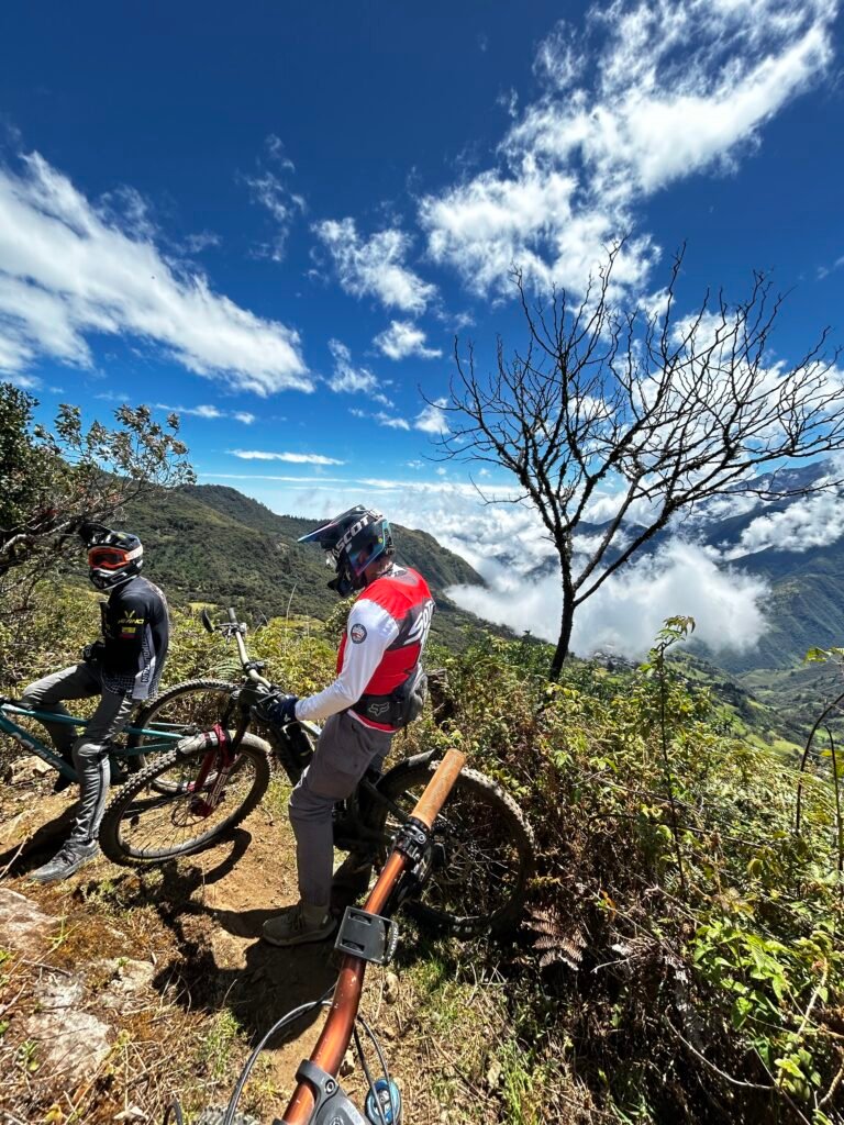 Two riders looking over a cloud-filled Andean valley