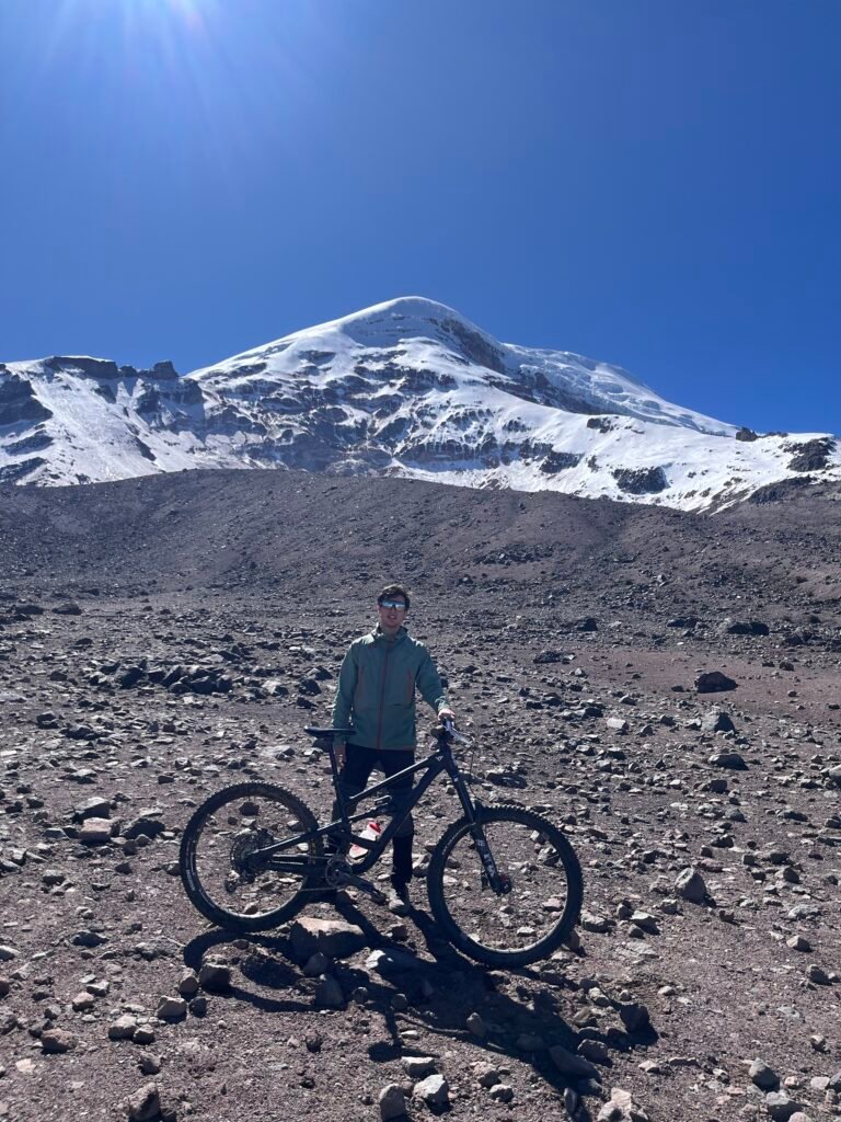 Rider with a bike below a snow-capped volcano